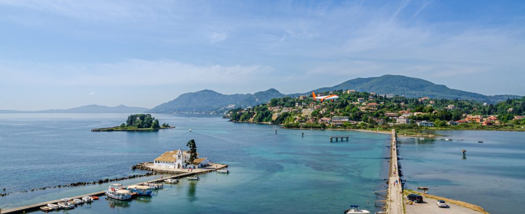 Passenger plane approaches Corfu airport during summer in Grecce Island of Corfu (Kerkyra) with mountainous terrain in the background.