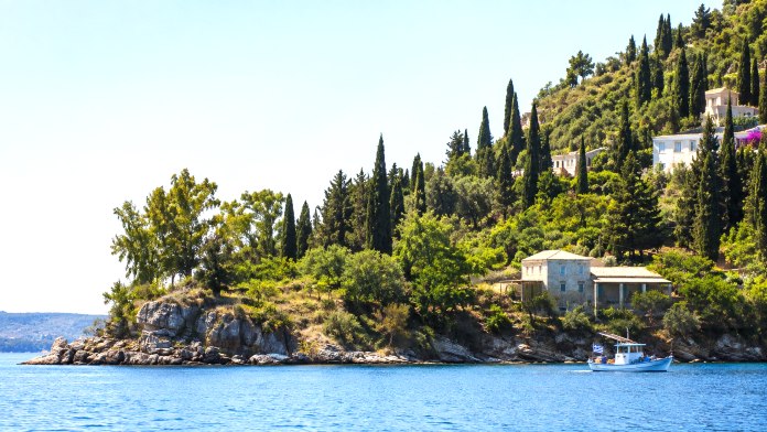 Traditional fishing boat along the green Corfu coastline