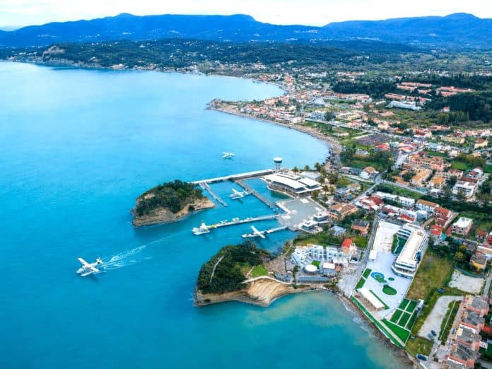 Aerial view of a coastal town in Corfu with a marina and seaplanes on the sea